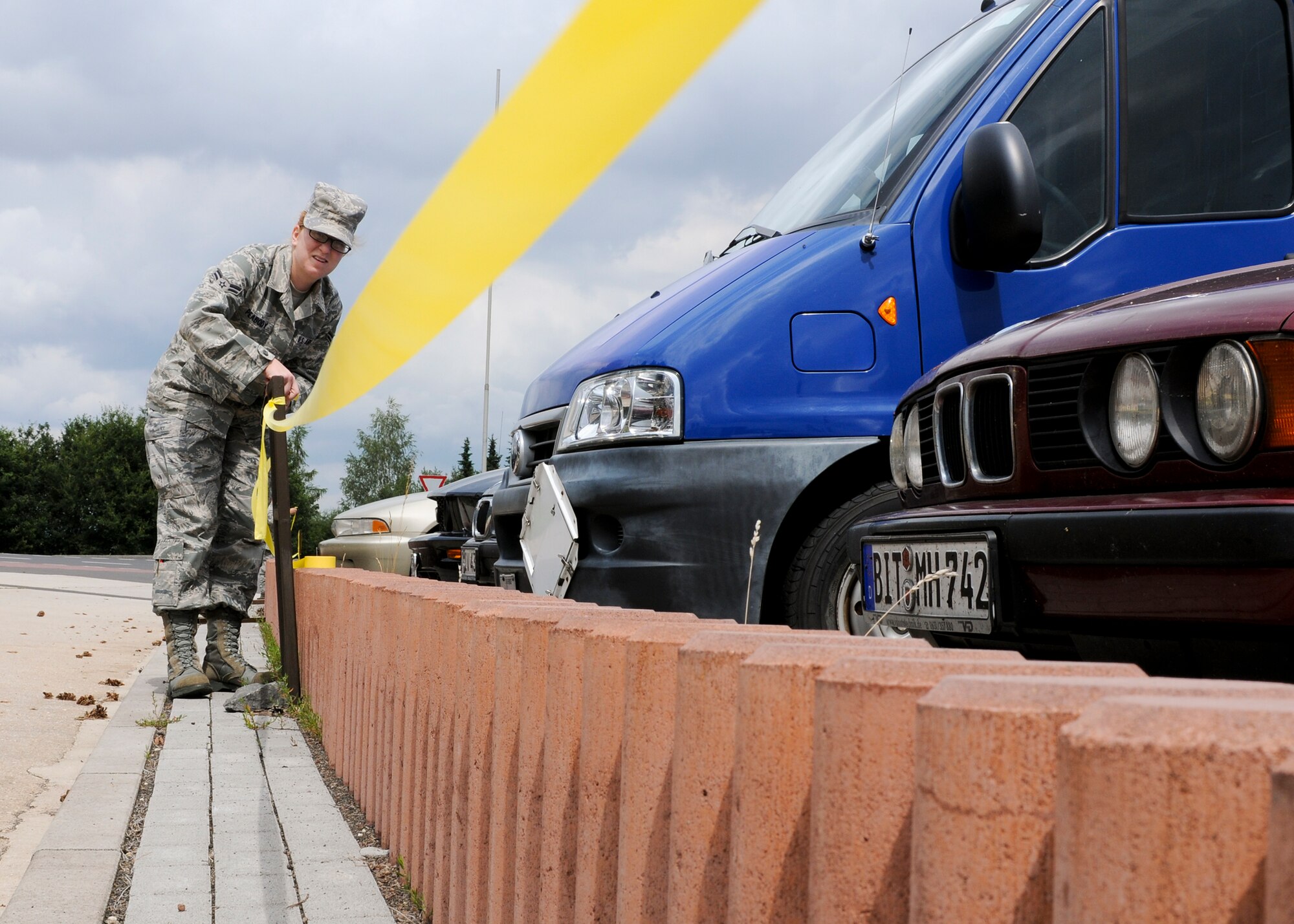 SPANGDAHLEM AIR BASE, Germany -- Airman 1st Class Christina Peabody, 52nd Medical Operations Squadron, prepares a cordon near the 81st Fighter Squadron Aug. 3 on Spangdahlem AB. The cordon was established to designate the boundaries of a simulated tactical area of responsibility for the upcoming Phase II exercise. The exercise will take place Aug. 4-7 in preparation for the 52nd FW’s NATO Tactical Evaluation next summer. (U.S. Air Force photo by Airman 1st Class Nathanael Callon)