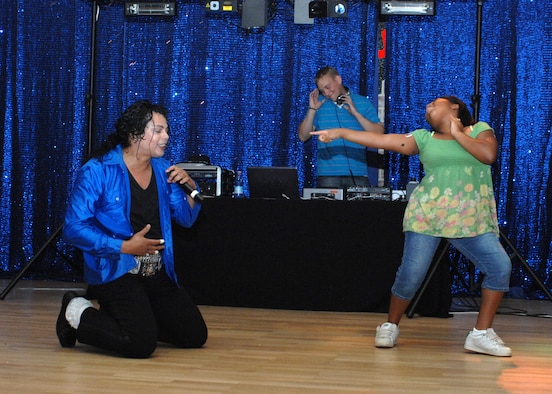 SPANGDAHLEM AIR BASE, Germany -- “Michael Jackson” performs as Arianna Warner, daughter of Domeca and Staff Sgt. Damon Clark, 52nd Maintenance Group, dances during the Michael Jackson Tribute Aug. 1 at the Brick House. The tribute included a performance by a Michael Jackson impersonator, a disc jockey, coloring sheets, music videos and a dance contest.  (U.S. Air Force photo by Senior Airman Jenifer H. Calhoun)