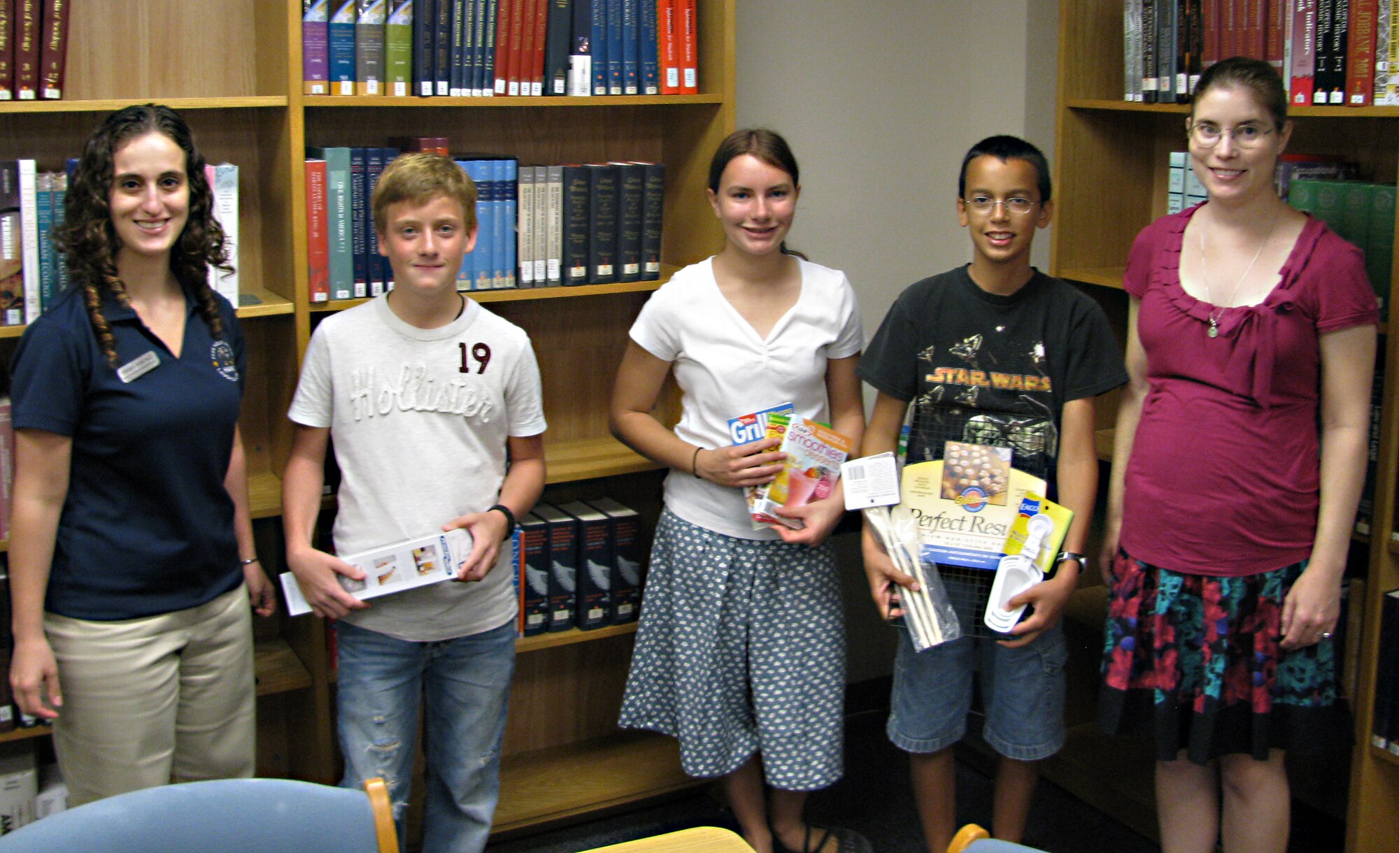 LAUGHLIN AIR FORCE BASE, Texas—Grisel Sanchez, 47th Force Support Squadron health education program manager, William Huber, Ben Jackey, Sarah Jackey, and Tricia Ross, library program coordinator, stand in Laughlin’s Bookmark Library after participating in a cooking contest for teens July 29.  William, Ben and Sarah are holding the prizes they won during the contest that was held to wrap up the library’s Teen Summer Reading Series, “Express Yourself.”  (Contributed photo) 