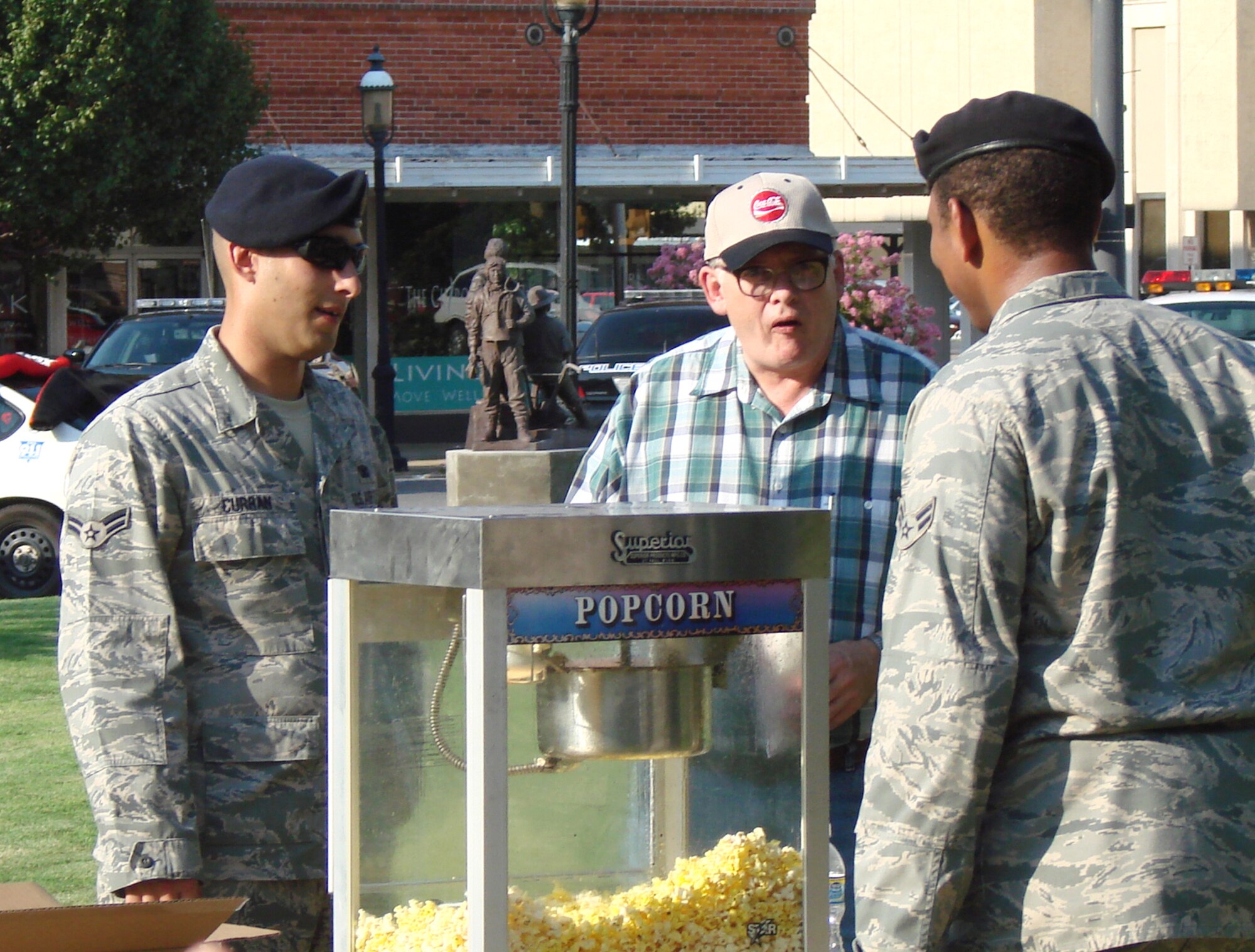 Airman 1st Class Joe Curran, left, and Airman 1st Class Amos Ford, right, talk with David Nicholson, a local clock maker, after giving him some popcorn during the National Night Out celebration Aug. 4, in Enid, Okla. Airmen Curran and Ford, with the 71st Security Forces Squadron at Vance AFB, volunteered, along with military working dog teams, to participate in the nation-wide celebration involving more than 15,000 communities. “What this represents is a solidarity movement of our citizens against crime,” said organizer, Deputy George Dillman, with the Garfield County Sheriff’s office. (U.S. Air Force photo/ Joe B. Wiles)