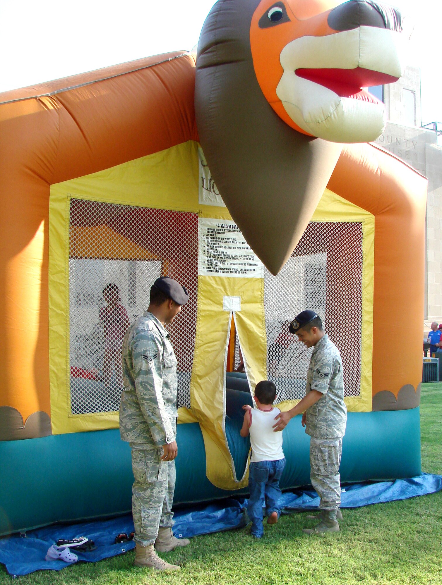 Airman 1st Class Amos Ford, left, and Airman 1st Class David Tangjian, help children get in and out of a bouncy house set up on the Garfield County Court House lawn in Enid, Okla., to celebrate the National Night Out Aug. 4. Airmen Ford and Tangjian, members of the 71st Security Forces Squadron at Vance AFB, volunteered, along with military working dog teams, to participate in the nation-wide celebration involving more than 15,000 communities. “What this represents is a solidarity movement of our citizens against crime,” said organizer, Deputy George Dillman, with the Garfield County Sheriff’s office. (U.S. Air Force photo/ Joe B. Wiles)