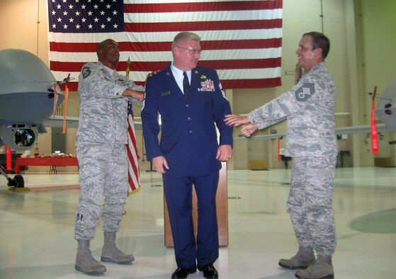 Chief Master Sgt. Shawn Smith, 432nd Operations Group chief enlisted manager (left), and Chief Master Sgt. Dean Cool, 926th Group maintenance chief (right), help pin on Chief Master Sgt. Steven Henderson's new rank during his promotion ceremony July 31.