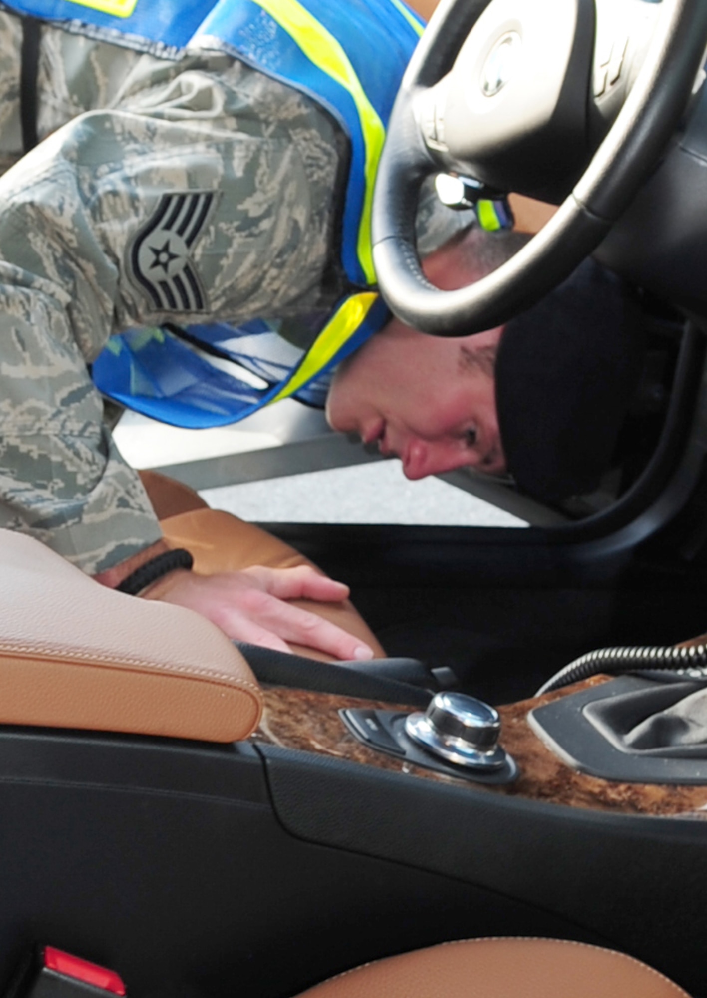 Staff Sgt. Darrell Stollings, 4th Security Forces Squadron patrolman, checks underneath a vehicle's seat during a random vehicle inspection on Seymour Johnson Air Force Base, N.C., July 31, 2009. Visual inspections of the engine, passenger compartments, and trunk are completed during the random vehicle inspections.  (U.S. Air Force photo by Airman 1st Class Rae Perry)
