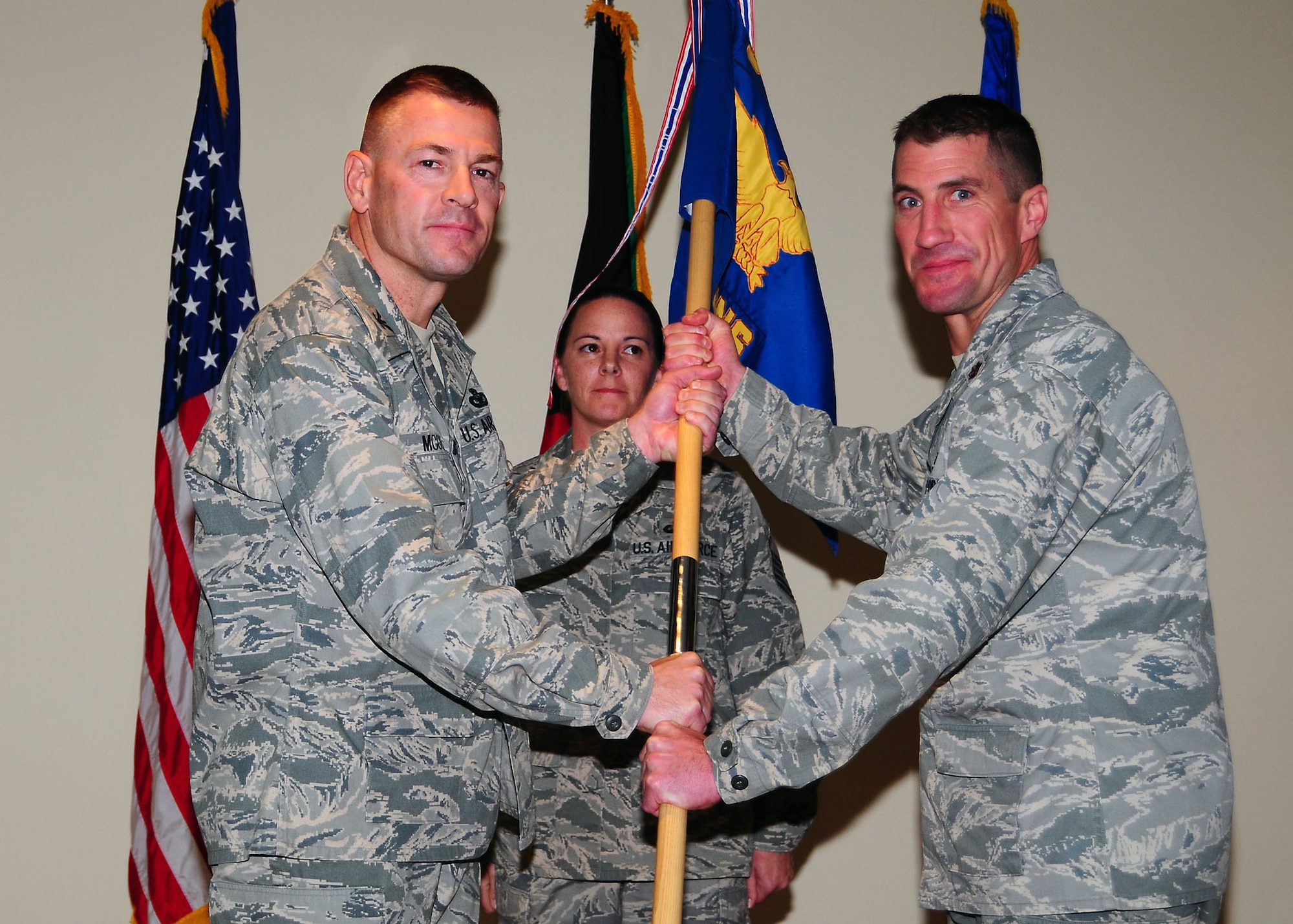 SOUTHWEST ASIA -- Maj. Robert McCabe, (right), assumes command of the 386th Expeditionary Contracting Squadron, by accepting the guidon from Col. Richard McComb, 386th Expeditionary Mission Support Group commander, during an assumption of command ceremony in Southwest Asia August 5.  (U.S. Air Force photo/Tech Sgt. Tony Tolley)