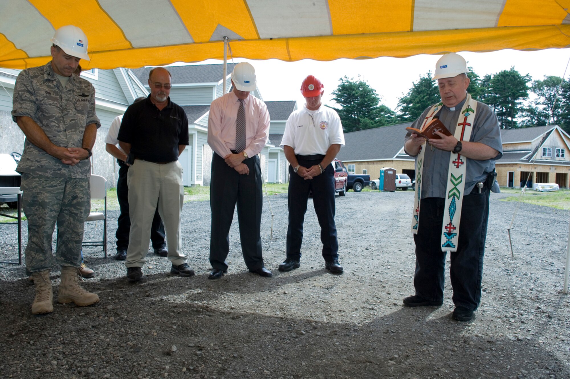 HANSCOM AIR FORCE BASE, Mass. –Rev. Lawrence Smith (right), of the Hanscom Base Chapel offers a blessing over the Hunt Pinnacle housing construction site and its workers during a ceremony on July 23 that marked the start of demolition work to make way for the construction of new homes for Hanscom residents. Col. Dave Orr, 66th Air Base Wing commander and Tim Stengel of Hunt Pinnacle spoke of the importance of the partnership between the base and HP to move forward on the delivery of new homes to Hanscom residents.  (U.S. Air Force photo by Rick Berry) 