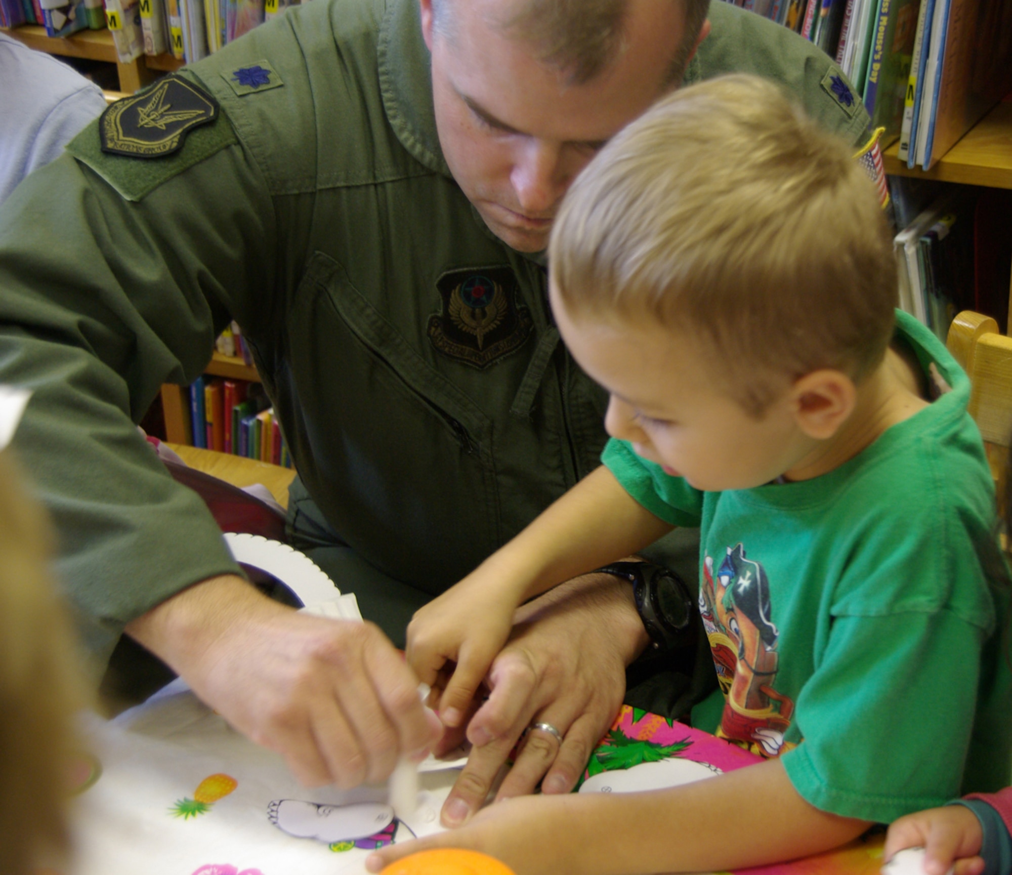 RAF MILDENHALL, England – Lt. Col. Rex Saukkonen, 352nd Special Operations Group director of staff, helps 5-year-old Alex Graham, son of Tech. Sgt. Thomas Graham, 352nd Maintenance Squadron, make a paper dinosaur during story time at the base library on July 29.  Colonel Saukkonen is one of three readers participating in “Leadership Reads” one of several projects sponsored by the American Red Cross in support of the nationwide “United We Serve” volunteer initiative sparked by President Barack Obama.  (U.S. Air Force photo by Tech. Sgt. Marelise Wood)