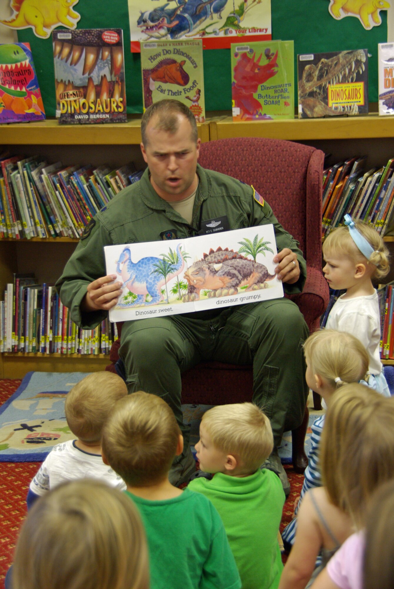 RAF MILDENHALL, England -- Lt. Col. Rex Saukkonen, 352nd Special Operations Group director of staff, makes a grumpy dinosaur face as he reads “Dinosaur Roar” to more than 30 children during story time at the base library on July 29.  Colonel Saukkonen is one of three readers participating in “Leadership Reads” one of several projects sponsored by the American Red Cross in support of the nationwide “United We Serve” volunteer initiative sparked by President Barack Obama.  (U.S. Air Force photo by Tech. Sgt. Marelise Wood)