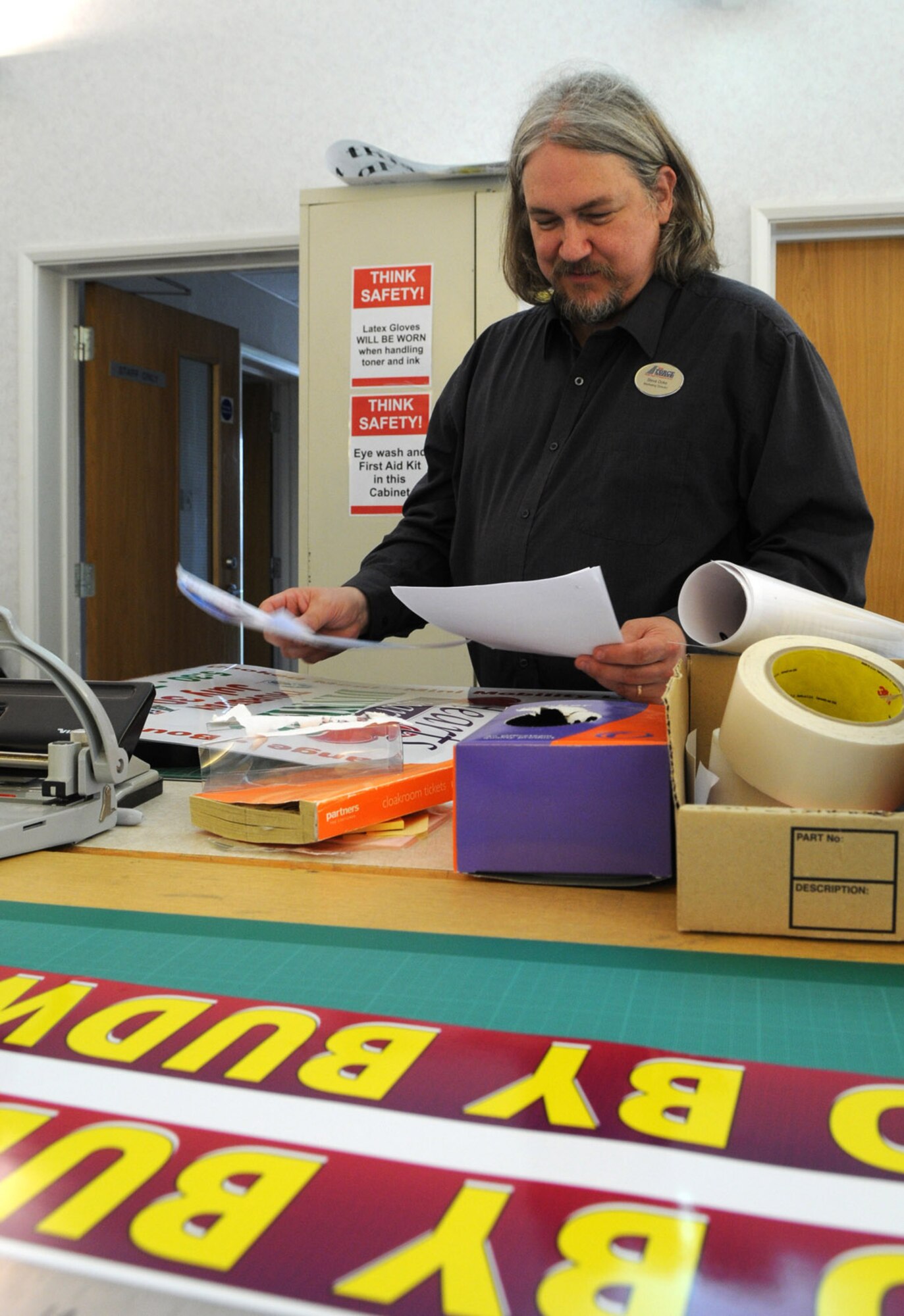 RAF MILDENHALL, England -- Steve Doke, 100th Force Support Squadron Marketing Director, looks over advertising products created by members of the five-person team.  The Marketing Department is responsible for getting the word about different promotions and events offered to Team Mildenhall.  (U.S. Air Force photo by Staff Sgt. Austin M. May)