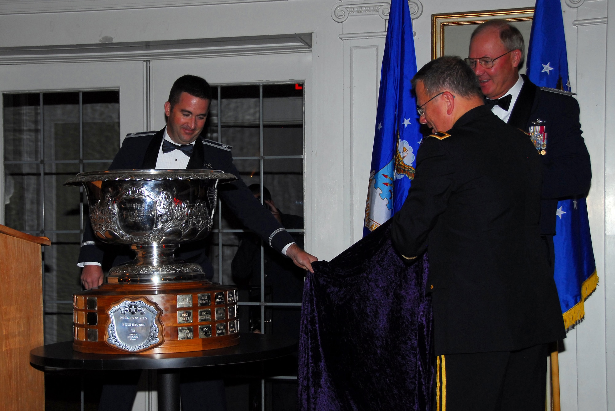 U.S. Air Force Lt. Col. Eric Chandler (left), Commander of the 179th Fighter Squadron, Duluth, Minn., along with General Craig R. McKinley-Chief, National Guard Bureau, and U.S. Army Major General Larry Shellito, Adjutant General of the Minnesota National Guard, unveils the prestigious Raytheon Trophy during the awarding presentation July 31, 2009 in Duluth, Minn.  The Raytheon Trophy was awarded to the 179th Fighter Squadron of the 148th Fighter Wing as the most outstanding air defense unit in the U.S. Air Force, marking only the fourth time an Air National Guard unit received this award since its inception in 1953.  (U.S. Air Force photo by Tech. Sgt. Brett R. Ewald)