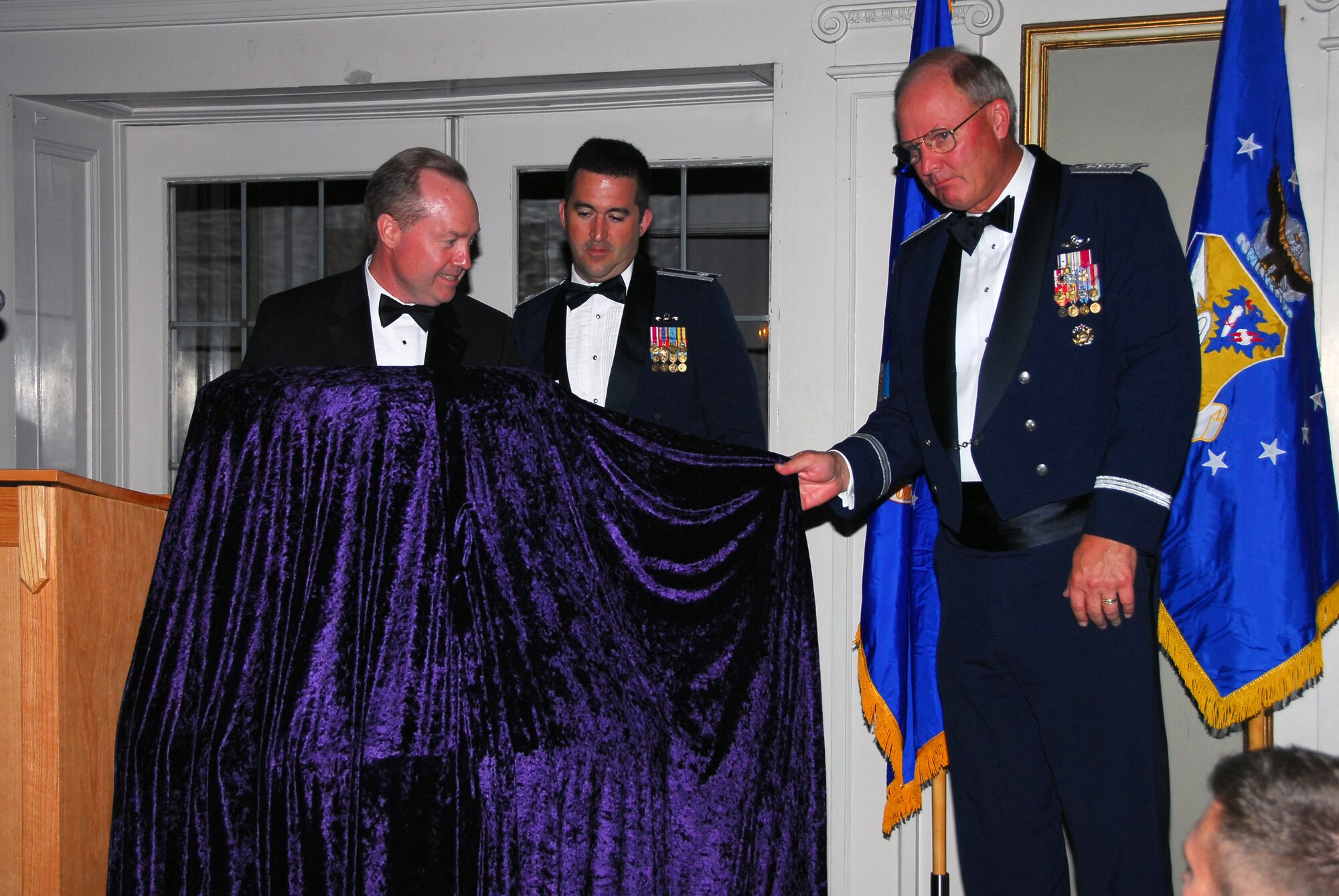 Dr. Thomas Kennedy, Vice President of Tactical Airborne Systems Space and Airborne Systems for the Raytheon Company (left), U.S. Air Force Lt. Col. Eric Chandler (center), Commander of the 179th Fighter Squadron, Duluth, Minn., and General Craig R. McKinley-Chief, National Guard Bureau, prepares to unveil the prestigious Raytheon Trophy during the awarding presentation July 31, 2009 in Duluth, Minn.  The Raytheon Trophy was awarded to the 179th Fighter Squadron of the 148th Fighter Wing as the most outstanding air defense unit in the U.S. Air Force, marking only the fourth time an Air National Guard unit received this award since its inception in 1953.  (U.S. Air Force photo by Tech. Sgt. Brett R. Ewald) 