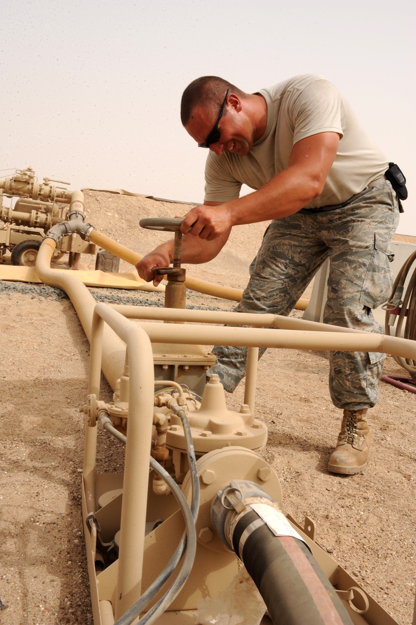 SOUTHWEST ASIA - Staff Sgt. Aaron Hastey, 380th Expeditionary Logistics Readiness Squadron, tightens a fill stand gate valve between refueling R-11 refuel trucks Aug 3. Sergeant Hastey is a fuels storage technician accountant from Fairchild Air Force base, Wash., and hails from Spokane, Wash. (U.S. Air Force photo Tech. Sgt. Charles Larkin Sr.)