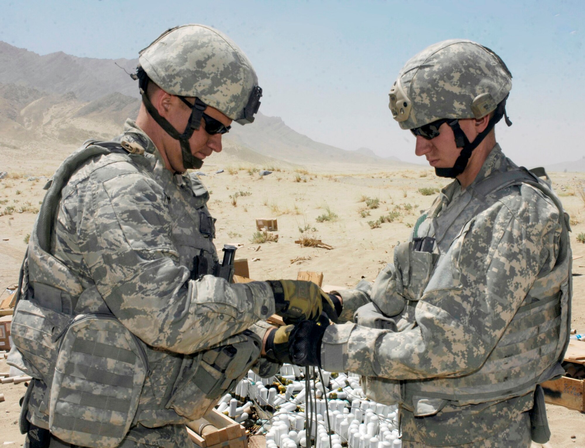 Staff Sgts. Trent Rydberg (left) and Greg Talley tape together wire leads that send firing signals to C-4 explosive charges attached to a cache of ordnance Aug. 2 at a disposal range near Bagram Airfield, Afghanistan. Several hundred pounds of mixed ordnance, including discarded Soviet munitions from the 1970s, were destroyed. The Airmen are explosive ordnance disposal technicians with the 755th Air Expeditionary Group. Sergeant Rydberg is deployed from Scott Air Force Base, Ill., and Sergeant Talley is deployed from Dyess AFB, Texas. (U.S. Air Force photo/Tech. Sgt. John Jung)