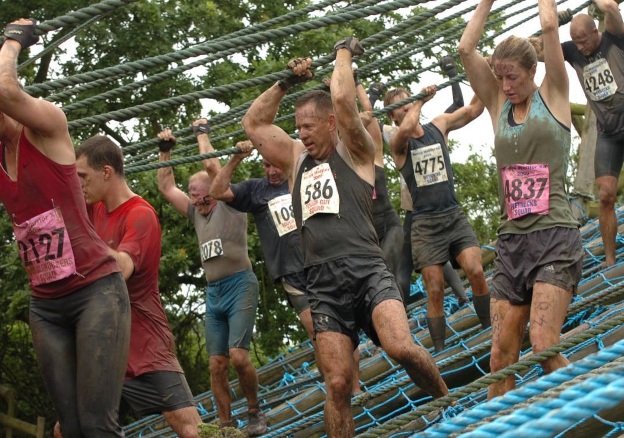 During UK TOUGH GUY summer 2009, Marine Corps Col. Pete Devlin, JIOCEUR Analytic Center (JAC) Commander, overcomes the behemoth described as : "a series of 4 towers over a bed of killer nettles. the first task is shimmying up a telegraph pole to the top of the first tower - don't be tempted to clamber up the blue netting, this is  to break your fall!" (U.S. Air Force photo by Staff Sgt. Rachel Goff)

