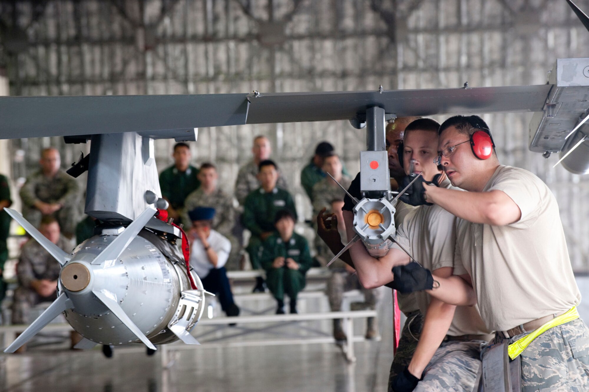 MISAWA AIR BASE, Japan -- A weapons load crew from the 35th Maintenance Operations Squadron secures an inert AIM-9X missile to the wing of an F-16 Fighting Falcon in front of an audience of Japan Air Self-Defense Force and U.S. Air Force Airmen July 31 in Hangar 911. The crew demonstrated the speed and precision in which they arm the fighter jets of the 35th Fighter Wing. (U.S. Air Force photo by Staff Sgt. Samuel Morse)
