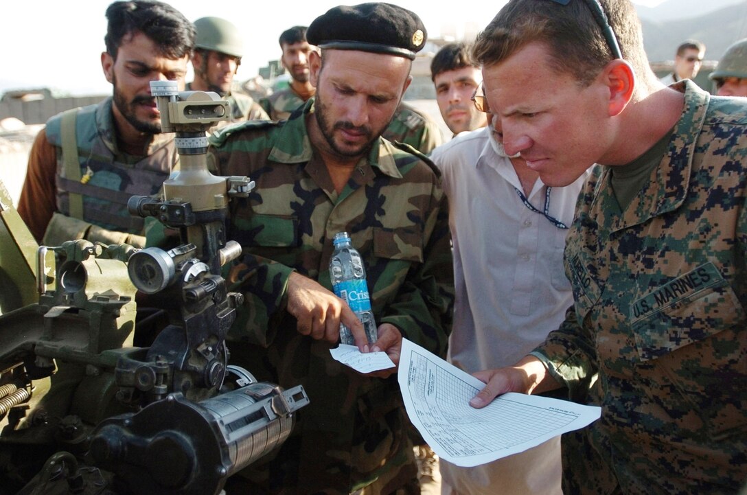 Marine Corps 1st Lt. Steve Murello of Embedded Training Team 4-4 listens as an Afghan officer explains the coordinates used during a live-fire exercise incorporating the Afghan army’s 4th Kandak forward observers, fire direction control personnel and artilleryman at Forward Operating Base Kalagush in Afghanistan’s Nuristan province, Aug. 2, 2009. U.S. Army photo by Sgt. Matthew Moeller