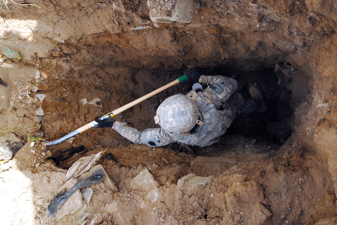 A U.S. Army soldier uses a shovel digging a hole searching for the remains of a U.S. servicemember missing in action since 2003, in Baghdad, Aug. 3, 2009.