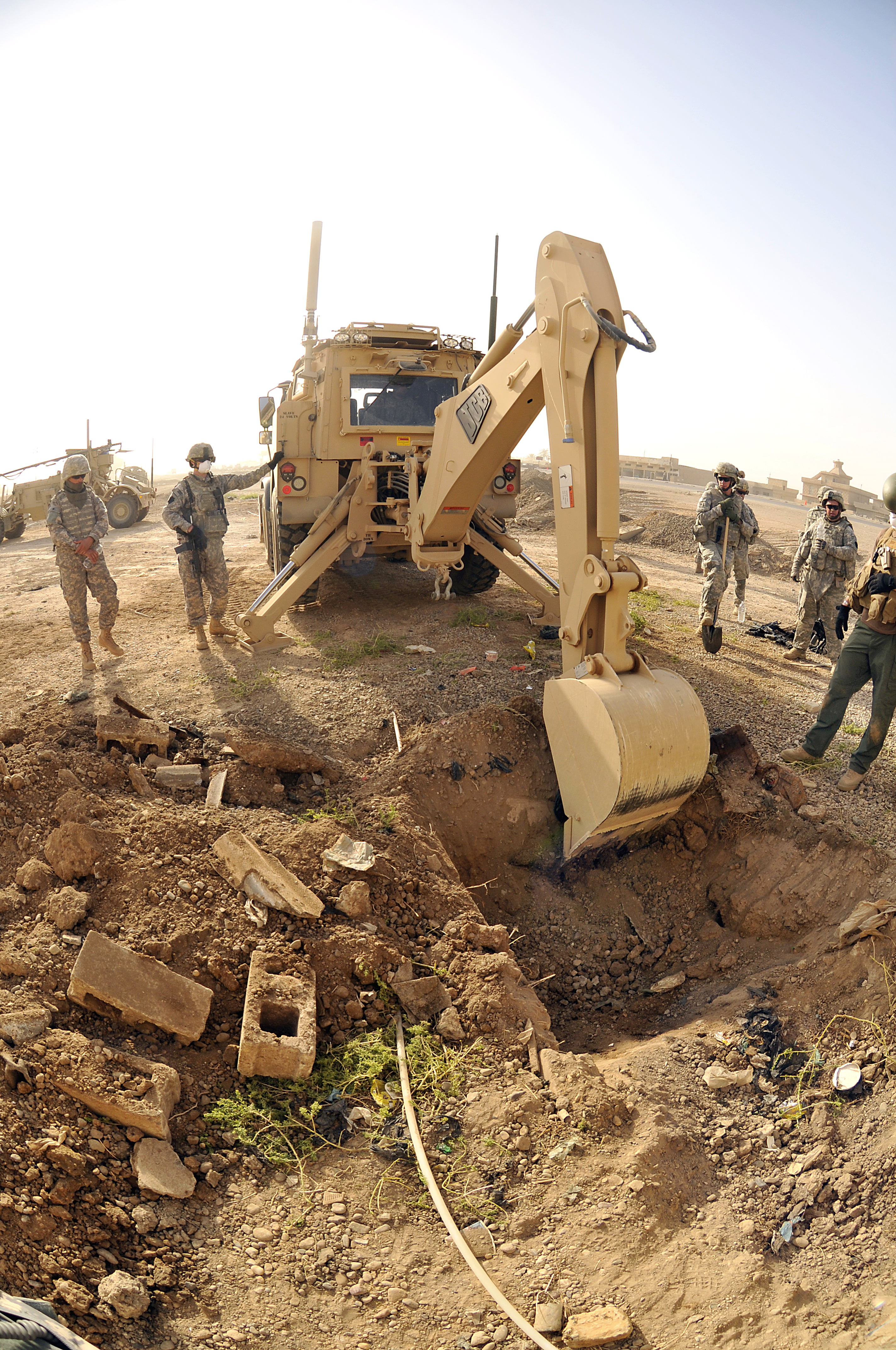 U.S. Army soldiers use a backhoe to dig a hole to search for the remains of