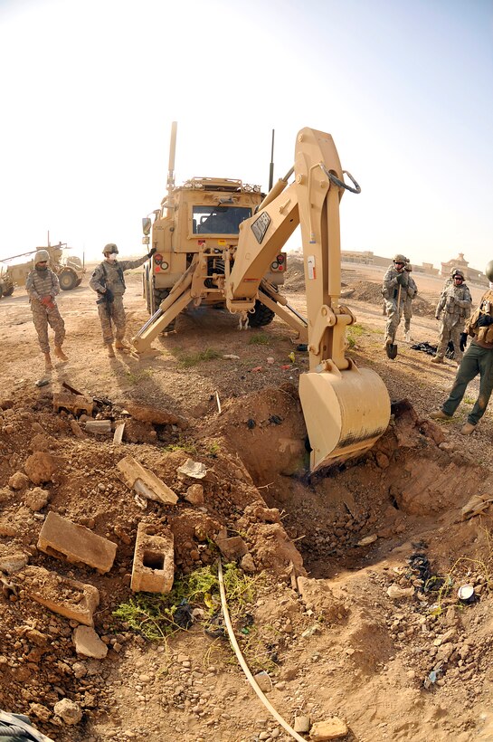 U.S. Army soldiers use a backhoe to dig a hole to search for the remains of a U.S. servicemember missing in action since 2003 in Baghdad, Aug. 3, 2009.