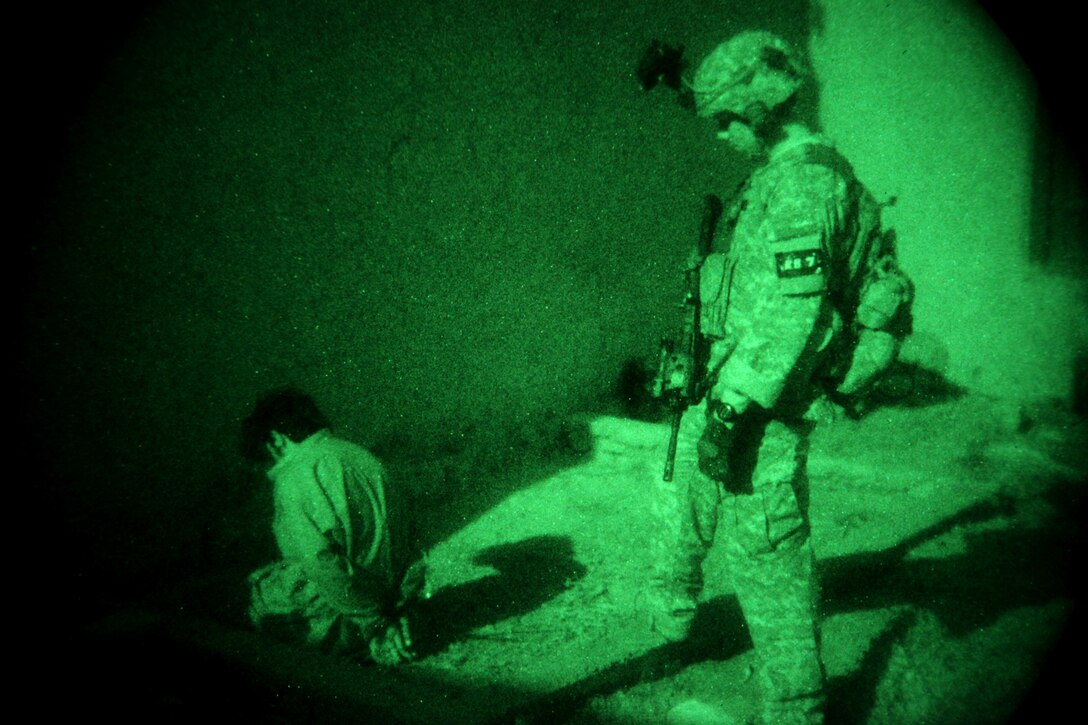 As seen through a night-vision device, a U.S. Army soldier guards a detainee during an air assault mission during Operation Champion Sword in Khost province, Afghanistan, Aug. 2, 2009.