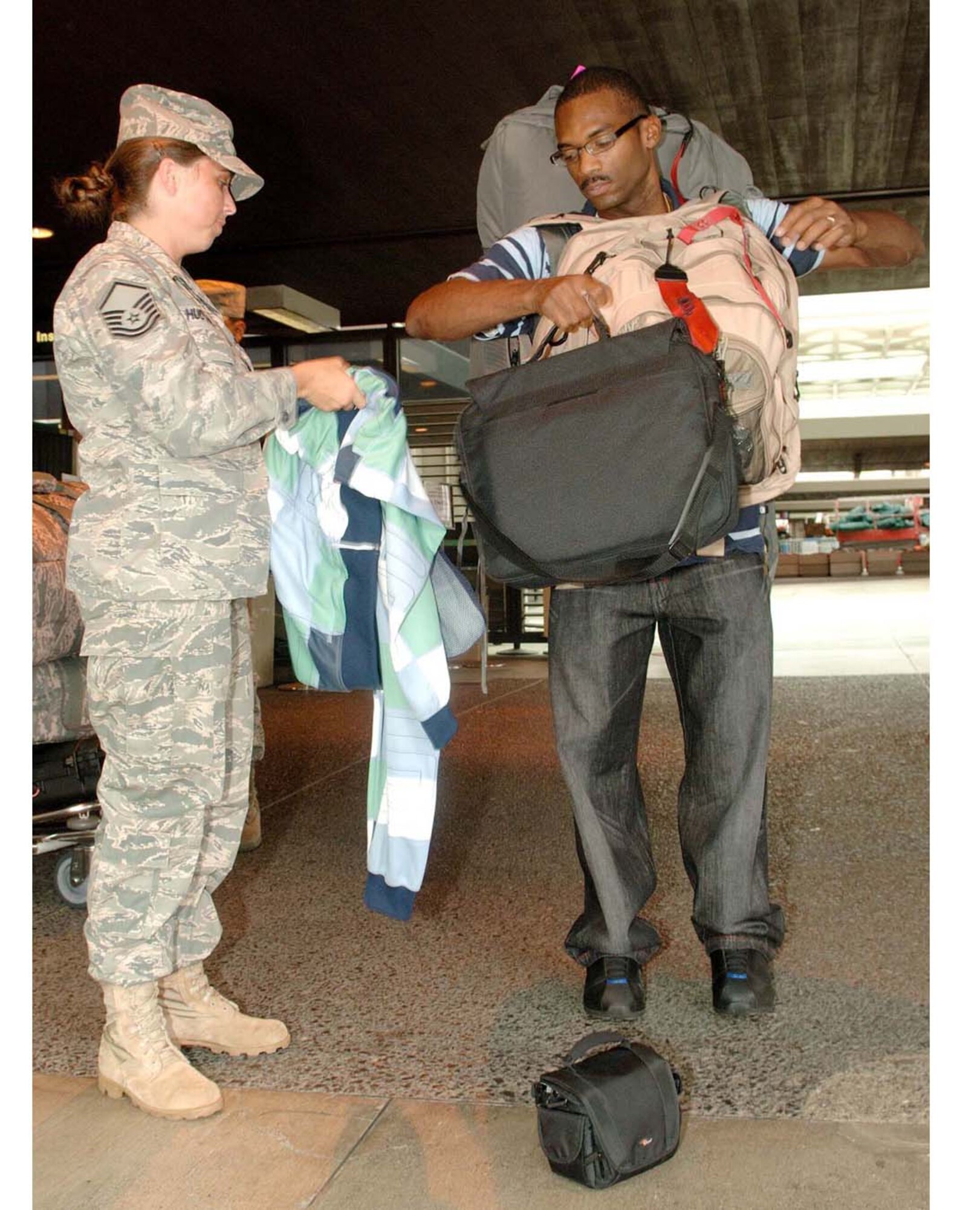 Master Sgt. Janet Hudson, 624th Regional Support Group Family Support, helps Tech. Sgt. Dedric Brown, 624th Civil Engineer Squadron, with his gear before he leaves the Honolulu (Hawaii) International Airport July 31, 2009. Fifty-four Air Force reservists from the squadron at Hickam Air Force Base were mobilized for six months of duty at Bagram Airfield, Afghanistan. (U.S. Air Force photo/Mark Bates)


