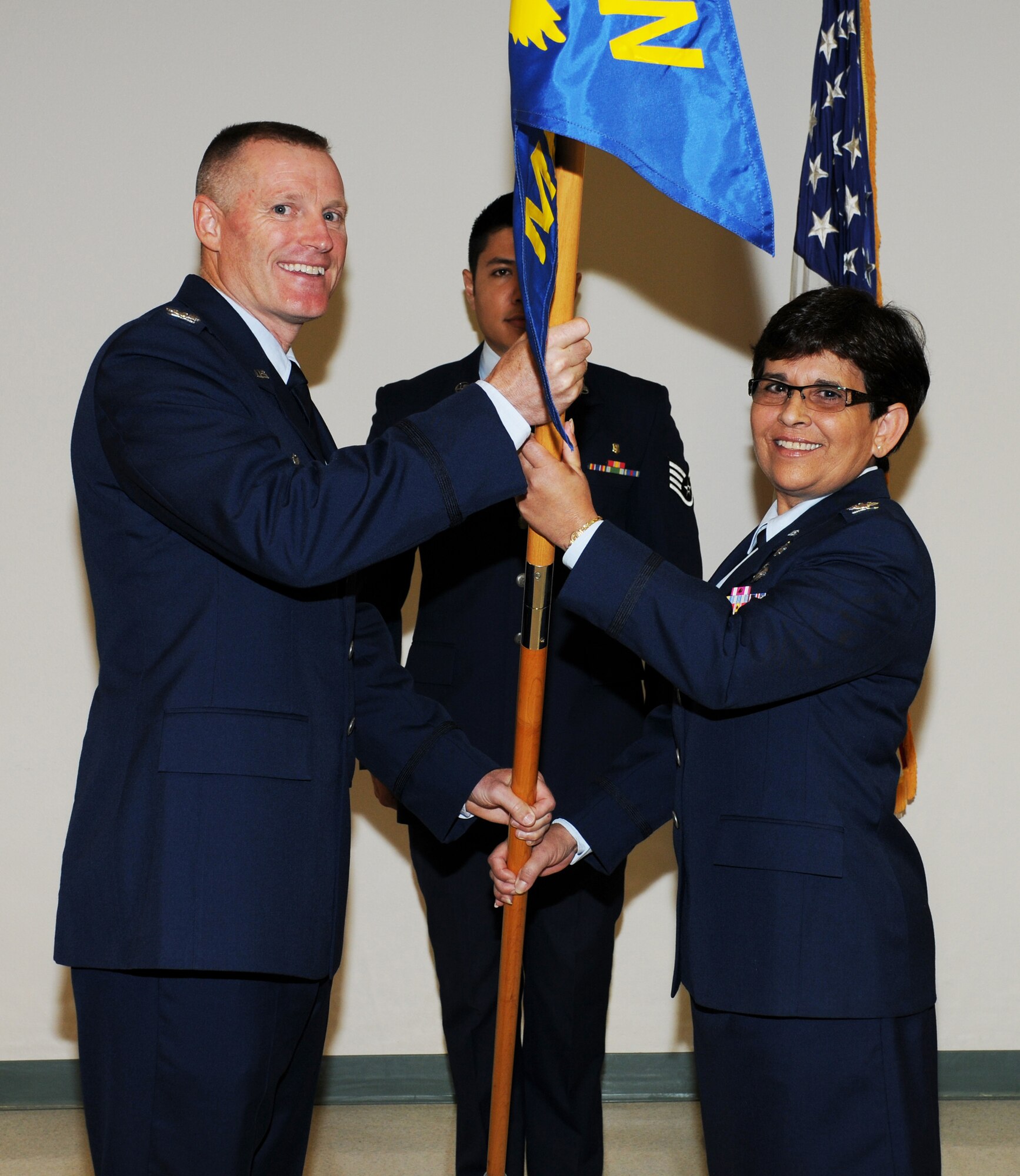 Colonel Kenneth D. Lewis, Jr., passes the flag to Colonel Maria D. Rodriguez during an assumption of command ceremony (U.S. Air Force Photo/Tech Sgt. Denise Hauser)