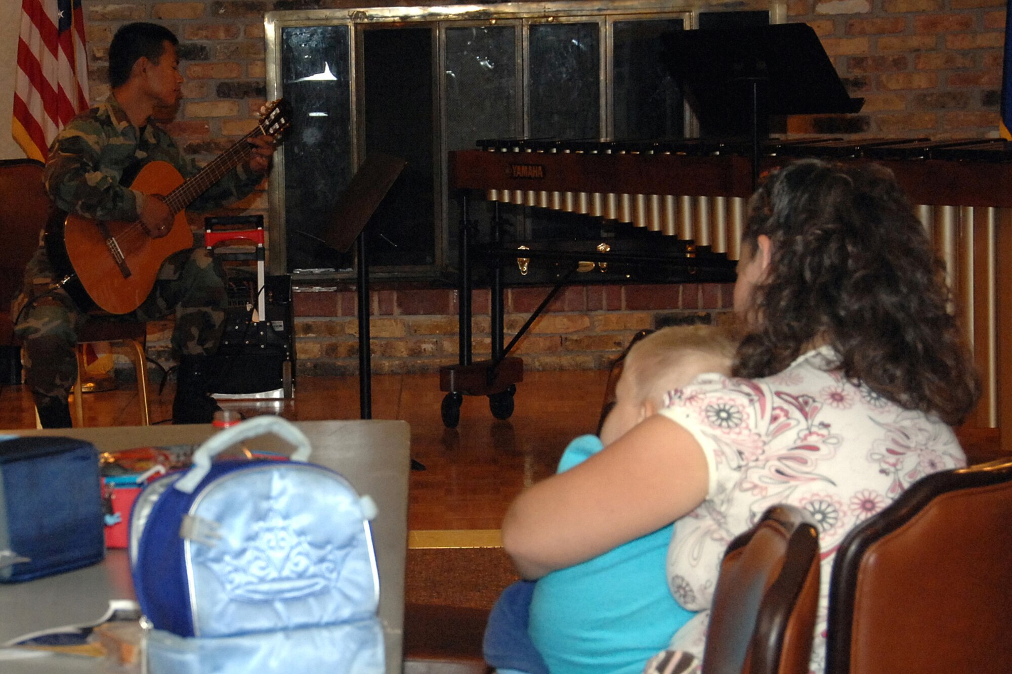 OFFUTT AIR FORCE BASE, Neb.-- Mara Neboshynsky, wife of Lt. Cmdr. Andrew Neboshynsky from STRATCOM, and son Matthew, listen to Senior Airman Daniel Santos, Heartland of America Band member, during the third Lunch Bachs concert at the Community Activity Center. The Lunch Bach is a free four-part series during the Offutt lunch hour. US Air Force photo by Kendra Williams