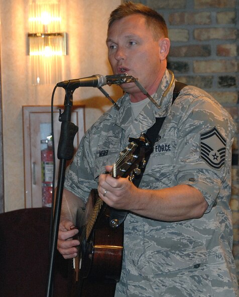 OFFUTT AIR FORCE BASE, Neb.-- Senior Master Sgt. James "Jimmy" Weber, superintendant for the Heartland of America Band, plays his guitar and harmonica and sings during the July 31 Launch Bach concert at the Community Activity Center. His songs for the concert include "Somebody Like You" by Keith Urban, "Piano Man" by Billy Joel, "Black Bird" by the Beatles, "Working Man's Blues" by Merle Haggard, "Wanted (Dead or Alive)" by Bon Jovi, and his own piece, "I Moved a Mountain." 