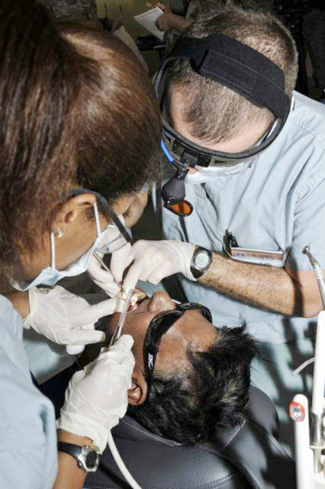 Maj.(Dr.) John Brewster and Airman 1st Class Tiffany Richard perform a tooth filling on a Guyanese man July 20 at the Diamond Primary School in Diamond, Guyana. The Airmen provided dental care to the local population for free during New Horizons Guyana, a $9 million exercise designed to strengthen ties with partner nations in Central and South America through combined quality of life improvement projects. Doctor Brewster is a dentist, and Airman Richard is a dental technician, both from the 59th Dental Training Squadron from Wilford Hall Medical Center at Lackland Air Force Base, Texas. (U.S. Air Force photo/Airman 1st Class Perry Aston) 