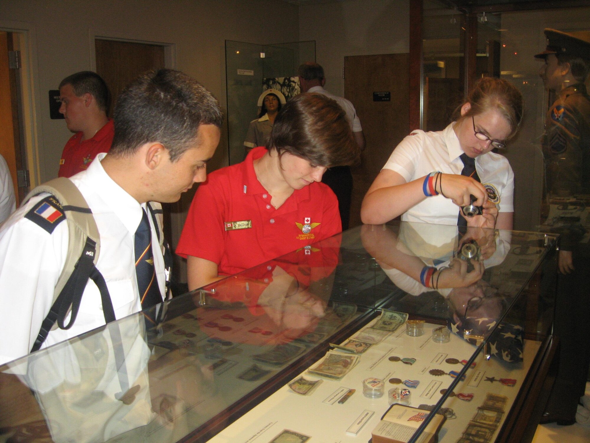 French Civil Air Patrol Cadet Karl Tricoche (left) explores an international coin display July 30 at Sheppard Air Force Base's Heritage Center with other members of the International Air Cadet Exchange program. Twelve international cadets toured Sheppard as part of the International Air Cadet Exchange program. (U.S. Air Force photo/Debi Smith)
