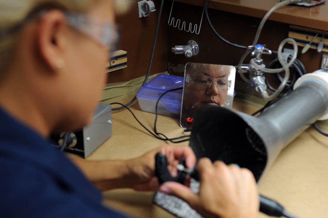 Master Sgt. Andrea Bates, 28th Medical Group NCO-in-charge of dental laboratory, removes excess molding from a mouthpiece using a circular handpiece here, July 30. The mouthpiece is used to protect teeth from damage by absorbing and evenly distributing shock, while keeping teeth covered. (U.S. Air Force photo/Airman 1st Class Adam Grant)
