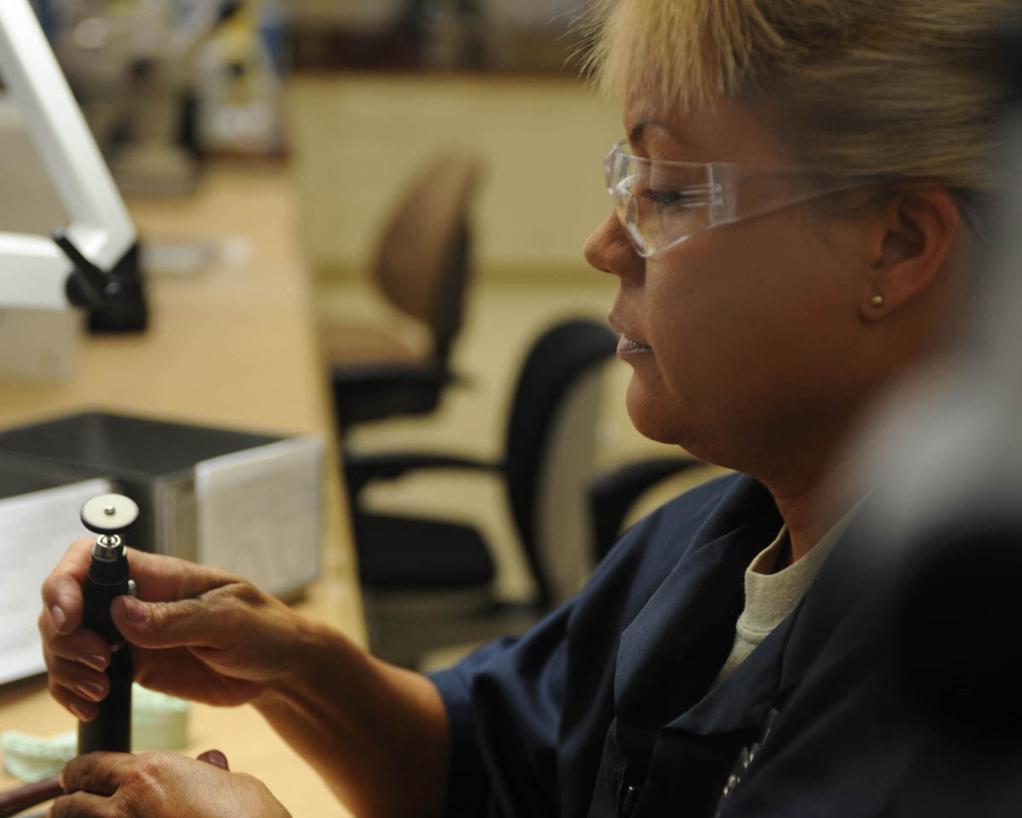 Master Sgt. Andrea Bates, 28th Medical Group NCO-in-charge of dental laboratory, examines a handpiece here, July 30.The handpiece is used to shape, mold and sculpt mouthpieces used to protect teeth during intramural activities. (U.S. Air Force photo/Airman 1st Class Adam Grant)