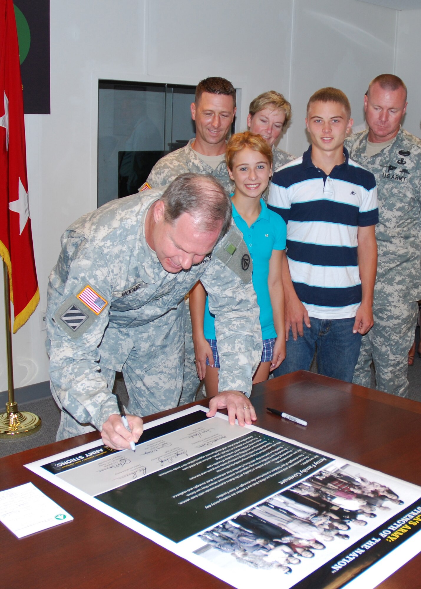 SCOTT AIR FORCE BASE, Ill. -- During a ceremony July 28, Army Maj. Gen. James L. Hodge, Surface Deployment and Distribution Command commander, signs the Army Family Covenant.  Master Sgt. Christopher Gish, his daughter, Kayla, and son, Austin, Col. Sheila McDonald, and Command Sgt. Maj. Thomas Mitchell also attended the signing. (Courtesy Photo)