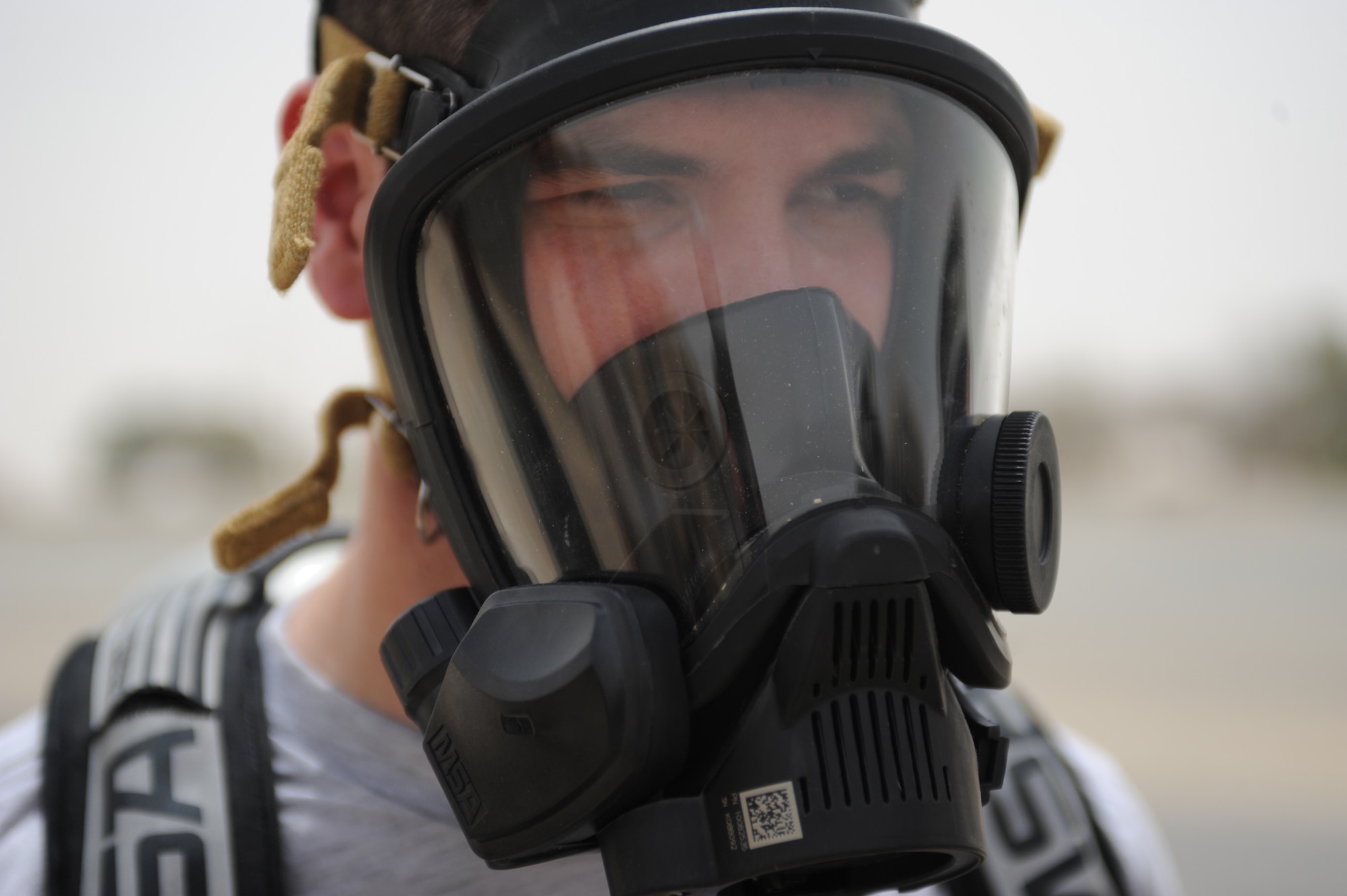 SOUTHWEST ASIA - Senior Airman Matthew Morris, 380th Expeditionary Civil Engineer Squadron, tests the fit on his mask before suiting up Aug 6. Airman Morris is an emergency management journeyman from Dover Air Force base, Del., and hails from Jefferson City, Mo. (U.S. Air Force photo Tech. Sgt. Charles Larkin Sr.)