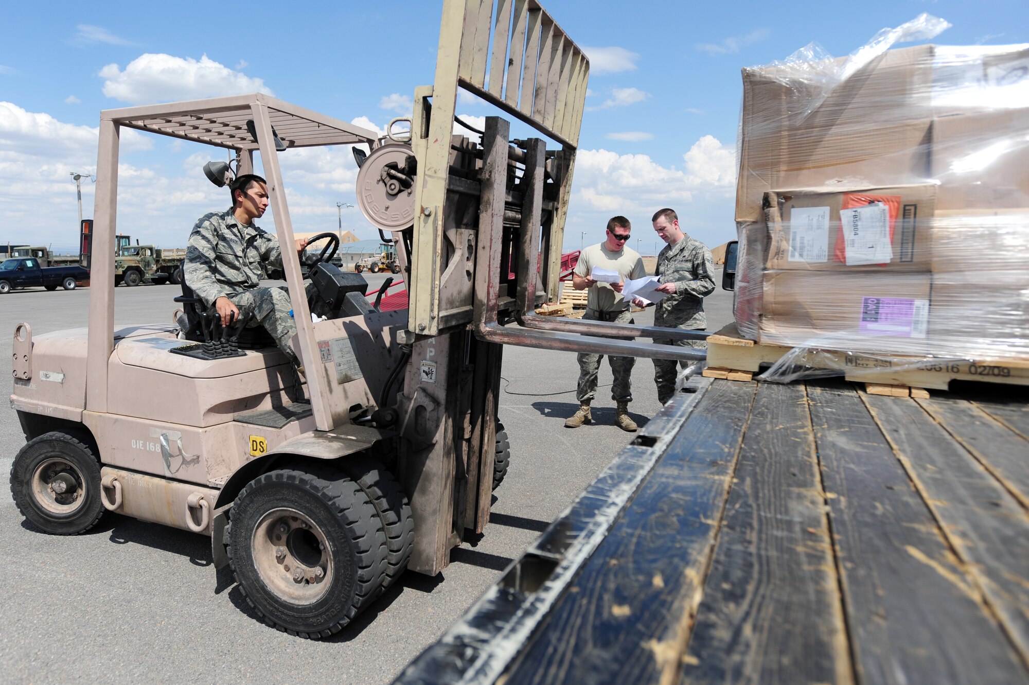 TRANSIT CENTER AT MANAS, Kyrgyzstan -- Supply Warehouse Journeyman Senior Airman Jorge Ontiveros, 376th Expeditionary Logistics Readiness Squadron, operates a forklift while Airmen 1st Class Joshua Lee and Ivan Hurd, 376th ELRS journeymen, verify shipment paperwork on products at the Transit Center at Manas. Ensuring correct products are delivered to the customer is a key first step in supply. Airmen Ontiveros and Hurd are deployed from the 100th LRS at the Royal Air Force Mildenhall, U.K. Airman Lee is deployed from the 366th LRS at Mountain Home Air Force Base, Idaho and is originally from Ashboro, N.C. Ontiveros is originally from El Paso, Texas while Hurd hails from Libby, Mont. (U.S. Air Force photo/Senior Airman Steele C. G. Britton)