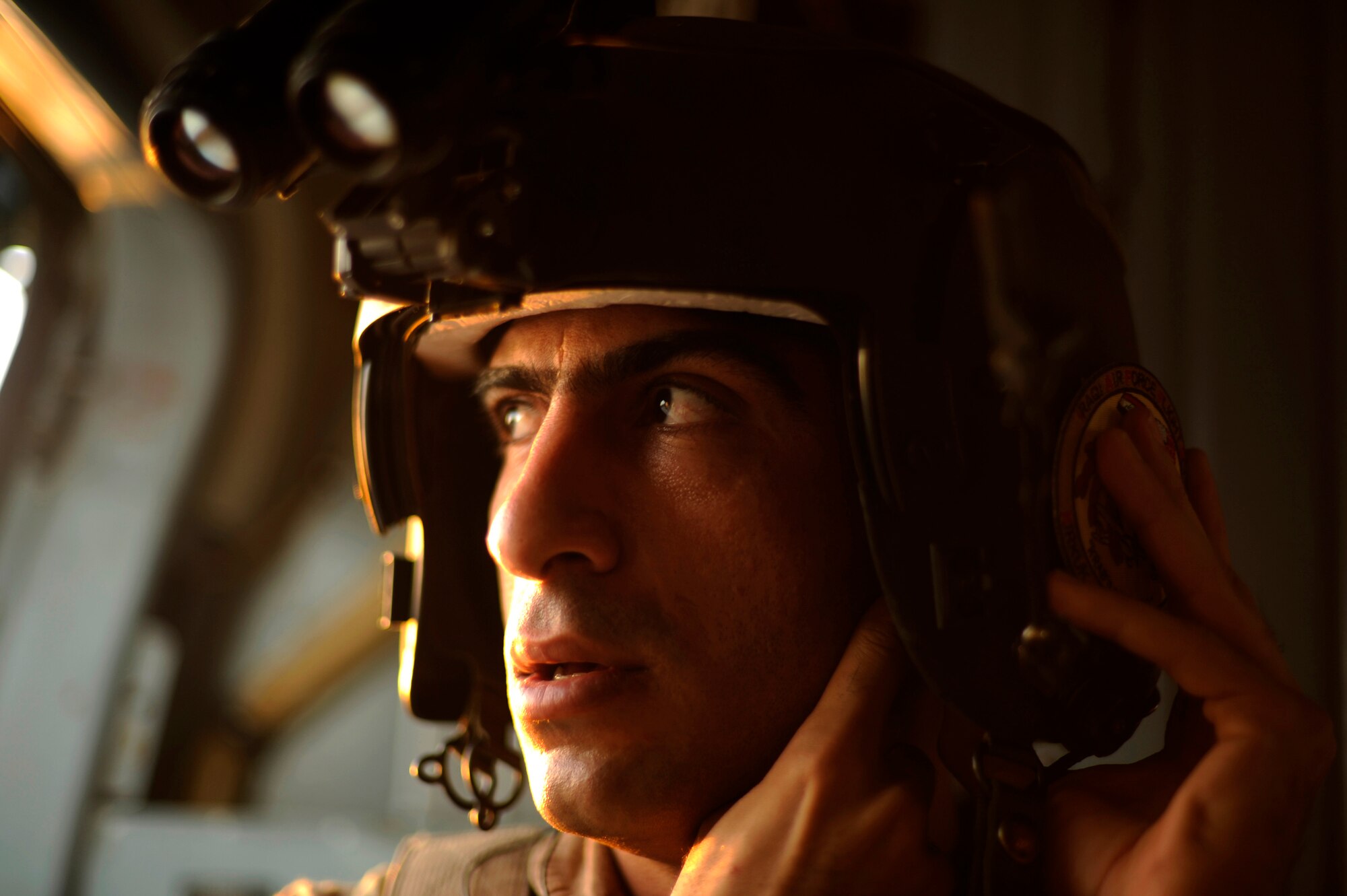 Iraqi air force aerial gunner Motaz Mande adjusts his helmet prior to a night mission onboard an Iraqi Mi-171 helicopter at Camp Taji, Iraq, July 19, 2009.  The American aircrew on this flight belong to the 721st Air Expeditionary Advisory Squadron that assists the Iraqi air force with many functions, including helicopter pilot training and aerial gunner training..  (U.S. Air Force photo by Staff Sgt. Michael B. Keller) (Released)
