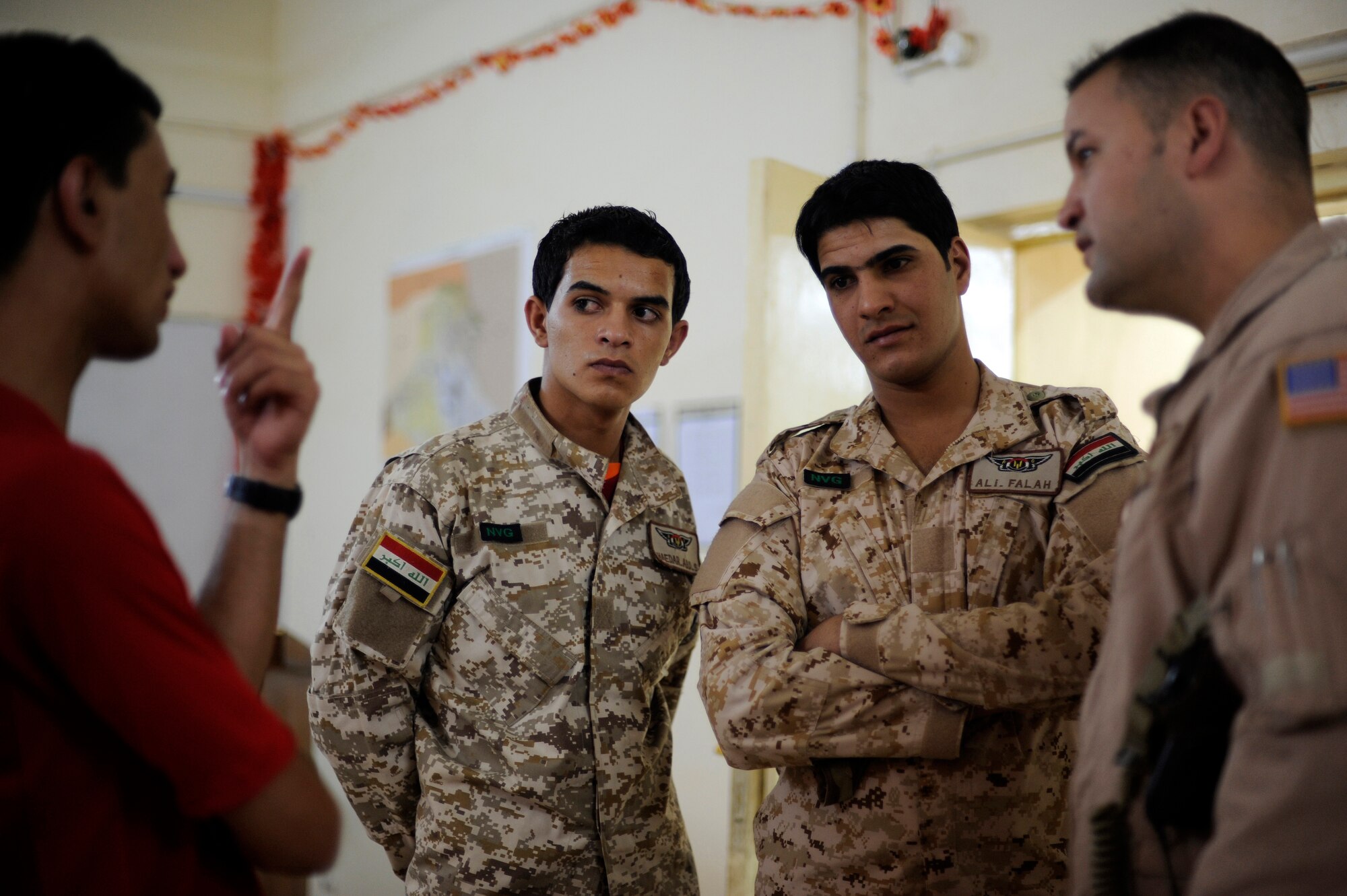U.S. Air Force Tech. Sgt. Onnez Rodriquez-Massas, far right, an aerial gunner with the 721st Air Expeditionary Advisor Squadron, speaks through an interpreter to two Iraqi air force aerial gunners prior to a night mission at Camp Taji, Iraq, July 12, 2009. Sergeant Rodriguez-Massas is deployed from Andrews Air Force Base, Md.  (U.S. Air Force photo by Staff Sgt. Michael B. Keller) (Released) 
