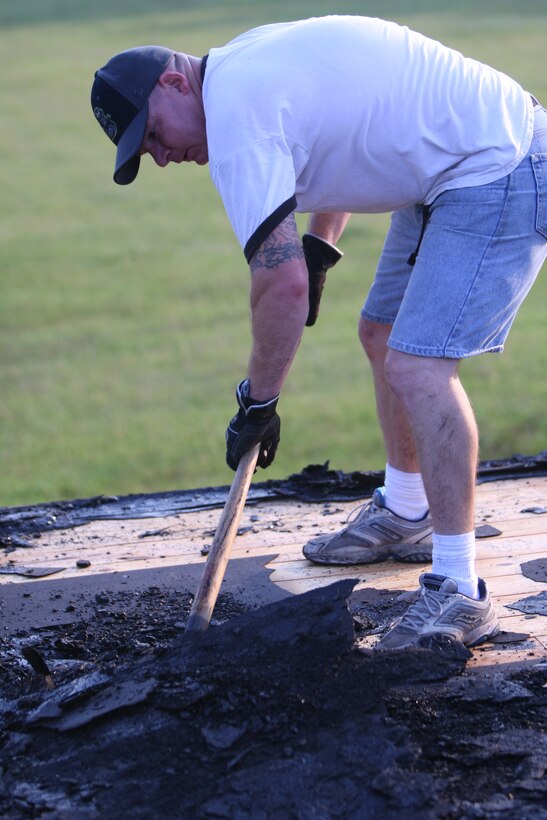 1st Sgt. Dennis Downing of 8th Engineer Support Battalion uses his shovel to gather pieces of tar on the roof of the Salvation Army building, August 8.