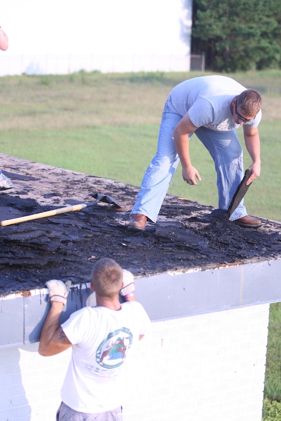 A Marine with 8th Engineer Support Battalion pulls himself onto the roof of the Salvation Army building as another Marine picks up pieces of tar, August 8. The Marines were part of a group of volunteers that helped the Salvation Army break down their roof so it could later be rebuilt.