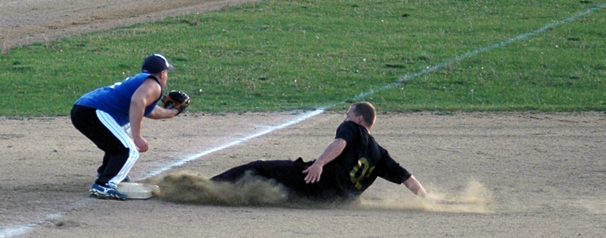 Russell Peacock, 341st Security Forces Group, waits for an incoming throw to third base as a runner from the 341st Maintenance Operation Squadron slides into the bag. 341st MOS edged out the 341st SFG 16 to 14 and went on to take second after nearly being shut out by the 12th Missile Squadron. (U.S. Air Force photo/Senior Airman Dillon White)