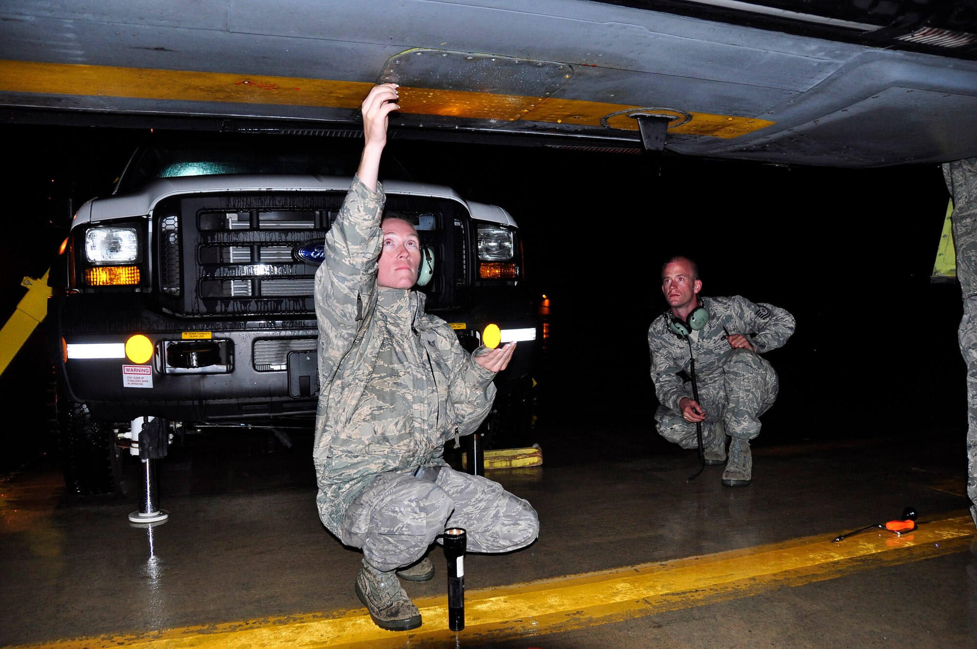 Tech. Sgt. Trevor Derenthal watches for leaking hydraulic fluid while Staff Sgt. Suann Becton removes screws to a panel on the bottom of a KC-135 Stratotanker that made an emergency diversion to Pease Air National Guard Base, N.H., on July 24. Both sergeants are Reservists assigned to the 931st Aircraft Maintenance Squadron at McConnell Air Force Base, Kan. (Courtesy photo/Lt. Col. Tsuyoshi Tung)   