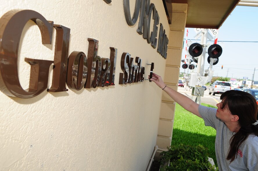 BARKSDALE AIR FORCE BASE, La. -- Kimberly Meek, local contractor, puts the finishing touches on the sign at the main gate highlighting the addition of Air Force Global Strike Command, Aug. 4. (U.S. Air Force photo by Senior Airman Joanna M. Kresge)