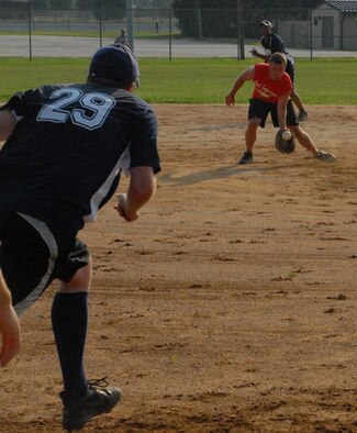 (Left) Joshua Solomon, 436th Communications Squadron, sprints toward first trying to beat the catch by the 436th Civil Engineering Squadron pitcher during an intramural softball game Aug. 3. The 436th CS beat 436th CES 5 - 4. (U.S. Air Force photo/Airman 1st Class Matthew Hubby)