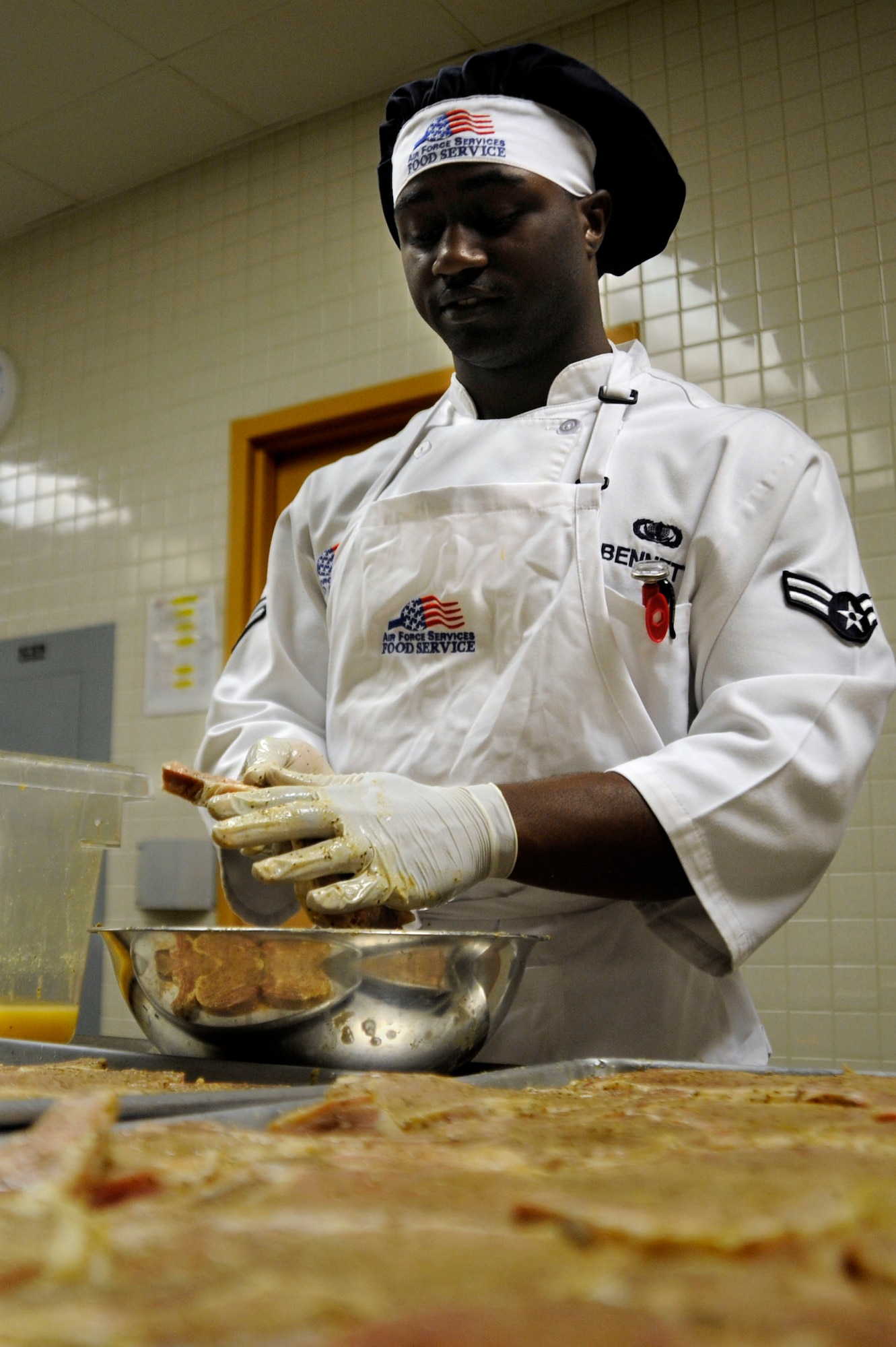 Airman 1st Class Alonzo Bennett prepares pork chops for the Dinner's Reef Dining Facility Top Chef competition here July 30. The Top Chef competition is held quarterly, it involves two teams with three members a piece competing for bragging rights and to get their names engraved on the Top Chef trophy. (U.S. Air Force photo by Staff Sgt. Joseph L. Swafford Jr./Released)