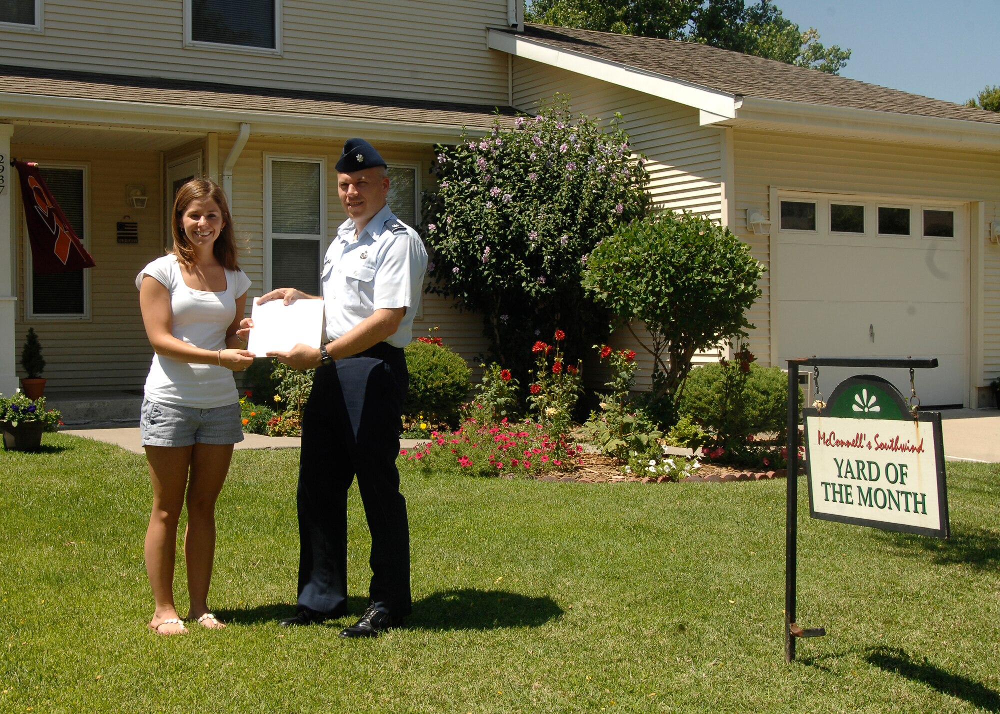 Lt. Col. Roman Hund, 22nd Mission Support Group deputy commander, recognizes Natasha Keene, spouse of 1st Lt. David Keene, 22nd Security Forces Squadron, for winning yard of the month at McConnell AFB, Kan., on Aug. 3. (U.S. Air Force photo/Senior Airman Anthony Mejia)