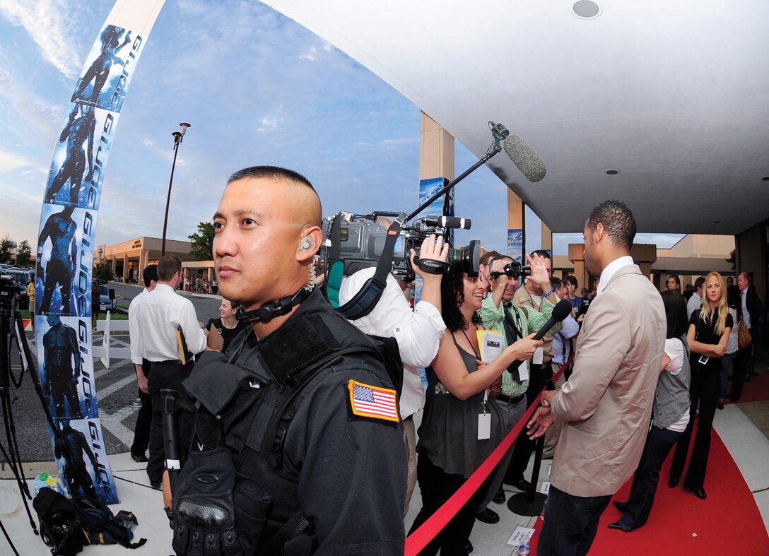 Technical Sgt. ElliJohn Macaraeg, 316th Security Forces Squadron military working dog trainer, provides security as actor Marlon Wayans takes part in an interview on the red carpet prior to the premiere of “G.I. Joe: The Rise of Cobra” at the Andrews base theater July 31. The movie is scheduled to hit theaters today. (U.S. Air Force photo/ Staff Sgt. Keyonna Fennell)