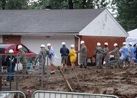 BEAVERCREEK, Ohio -- Volunteers from Wright-Patterson Air Force Base form a bucket-brigade of sorts to help move plants for the Terpenning family's new yard. The August 4 rain was heavy, but did not stop construction on the house. (Air Force photo by Ron Fry)
