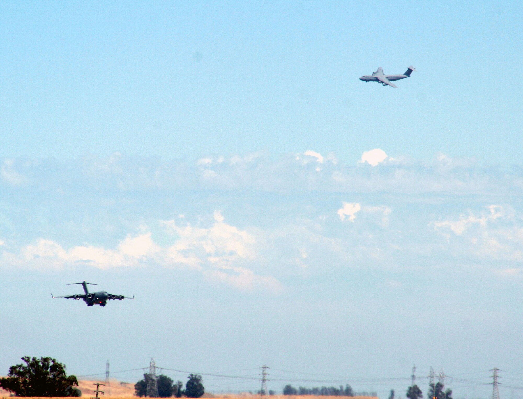A C-17 Globemaster III from the 60th Air Mobility Wing comes in for a landing while a C-5 Galaxy circles far behind in the sky at Travis Air Force Base, Calif., on Aug. 5, 2009. (U.S. Air Force Photo/Tech. Sgt. Scott T. Sturkol)