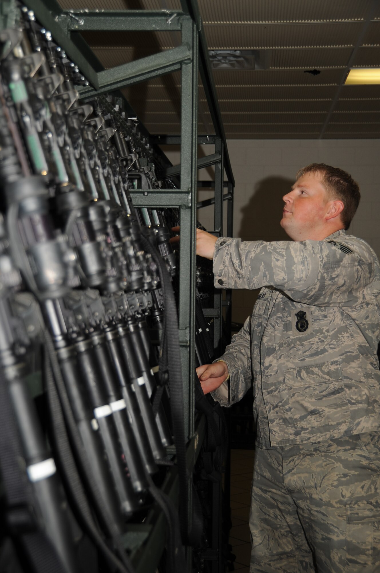 Staff Sgt. Jeremy Douglas, 28th Security Forces Squadron armory NCO in charge, puts away a M4 assault rifle here, August 6.  The weapon was turned in by Airman 1st Class Ninive Pena, 28 SFS patrolman, after his shift. (U.S. Air Force photo/Airman 1st Class Anthony Sanchelli)