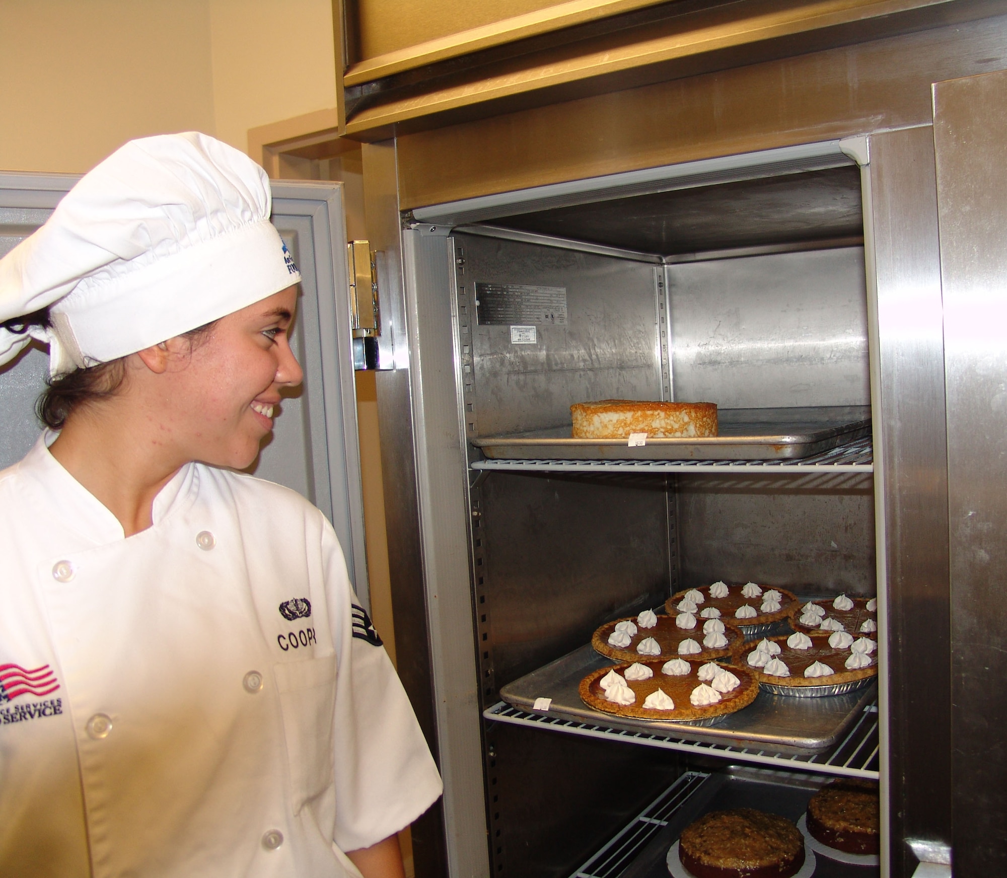 Senior Airman Roselyn Cooper checks out the supply of pies in the cooler.  The desserts are baked in-house daily. (USAF photo/Lois Walsh)                           