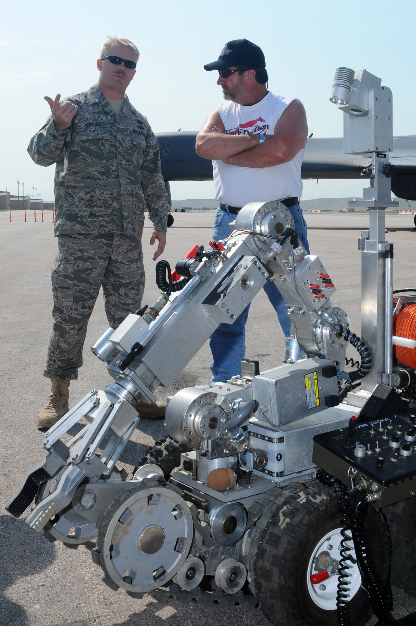 Senior Airman Beau Grabow, 28th Civil Engineer Squadron explosive ordnance disposal journeyman, talks to Michael Hess, from Angola, Ind., about a robot here, August 4. Mr. Hess is one of more than 400 motorcyclists who came out to Ellsworth for the Ninth Annual Dakota Thunder Motorcycle Run. (U.S. Air Force photo/ Senior Airman Kasey Zickmund)